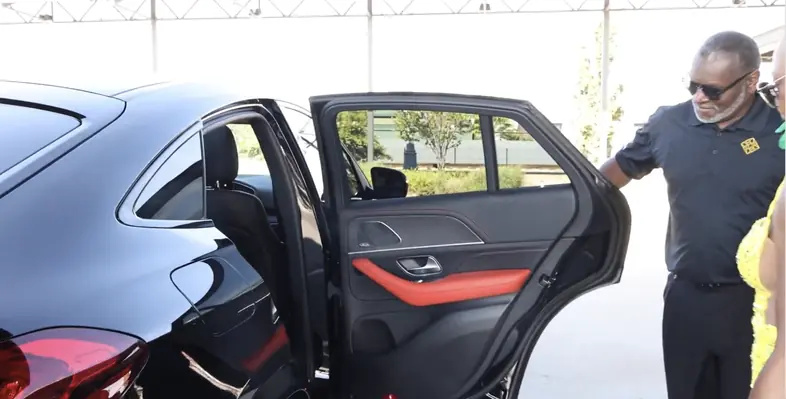 luxury chauffeur opening the door to a black coupe for an executive client