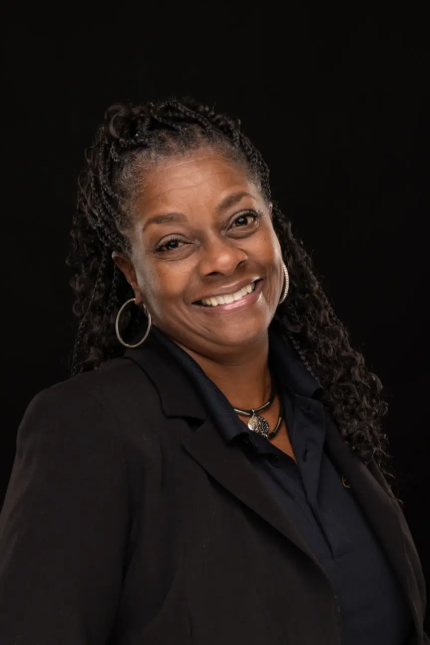 a black woman with long hair, smiling, wearing a nice coat