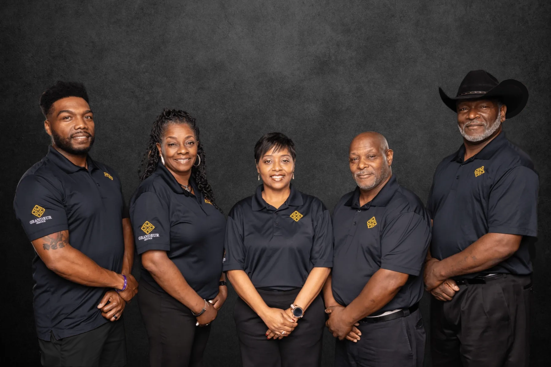 mixed group of black people wearing matching black polo shirts with a gold diamond logo on the chest and sleeve