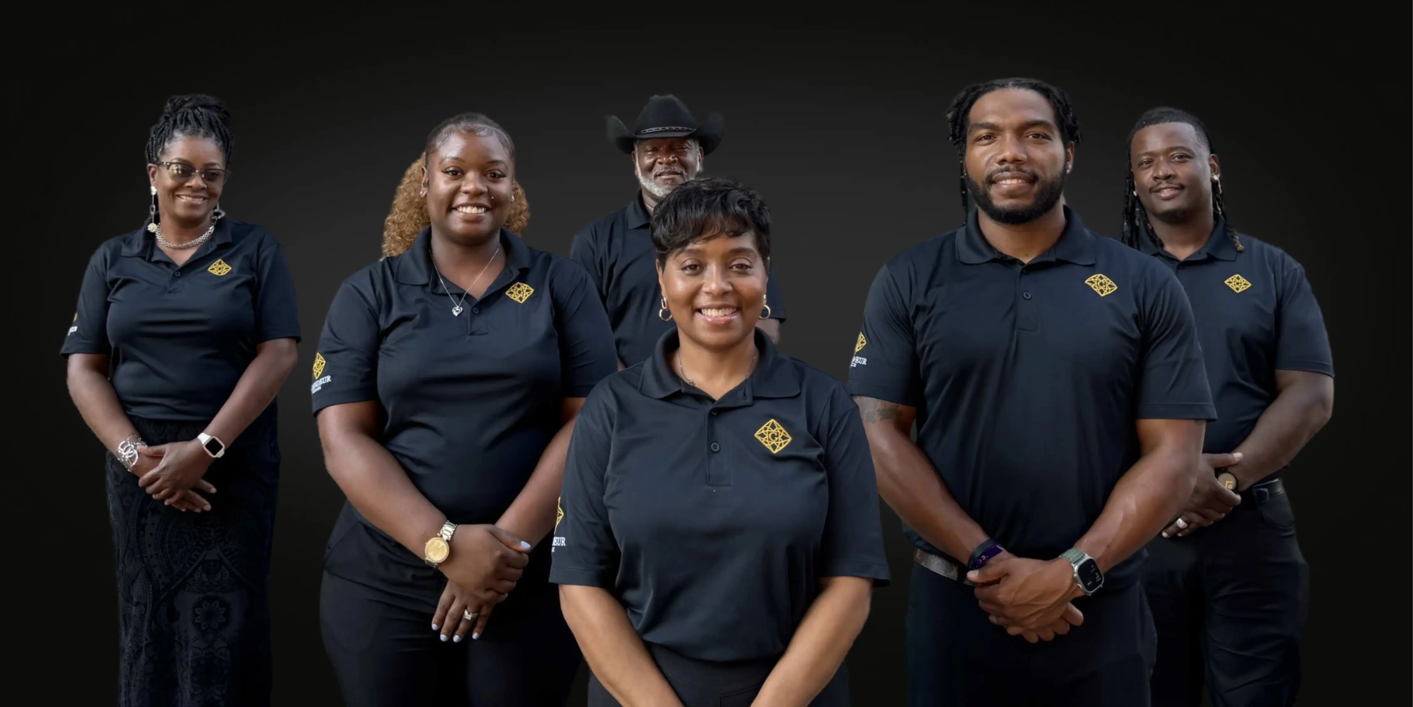 Group of Black chauffeurs in matching black polos with gold diamond logo, standing together and smiling