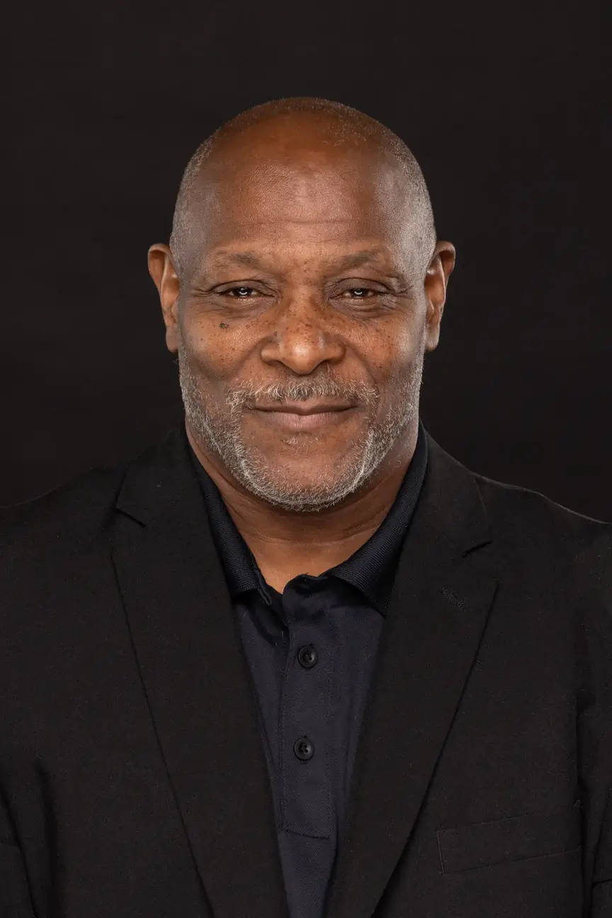 a bald, older black man with a stubble goatee wearing a sport coat