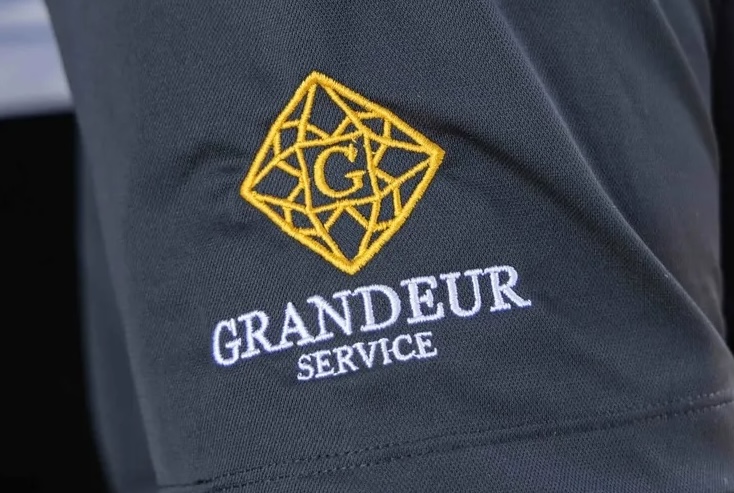 luxury chauffeur wearing a shirt with Grandeur Service logo embroidered on it