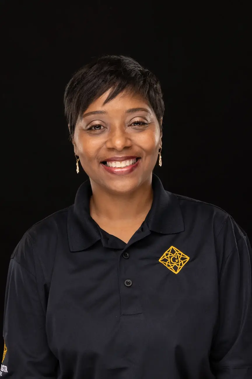 black woman, smiling, in a black polo shirt with a short haircut and muted red lipstick